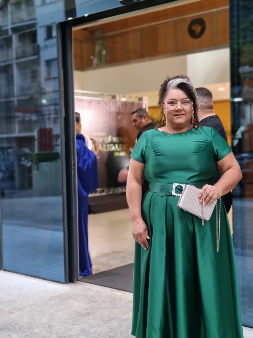 Sol Lima com vestido verde na entrada de um ambiente.