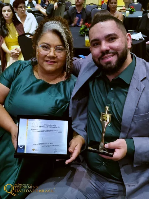 Sol Lima posa ao lado de um acompanhante com a placa e o troféu do prêmio.