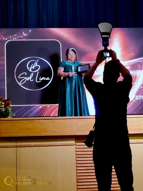 Fotógrafo registra Sol Lima com a premiação diante do palco da cerimônia.