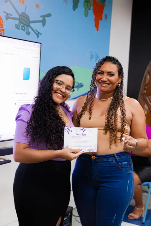 Duas participantes posam juntas com um material do encontro.