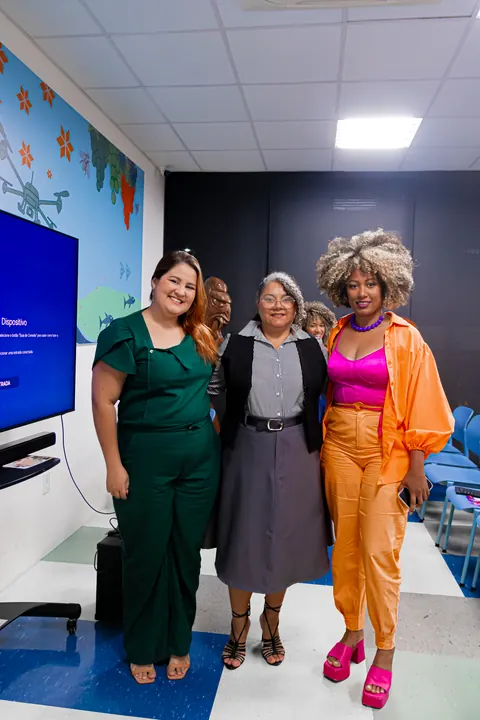 Três mulheres posam juntas ao fim de uma atividade do TPMe.